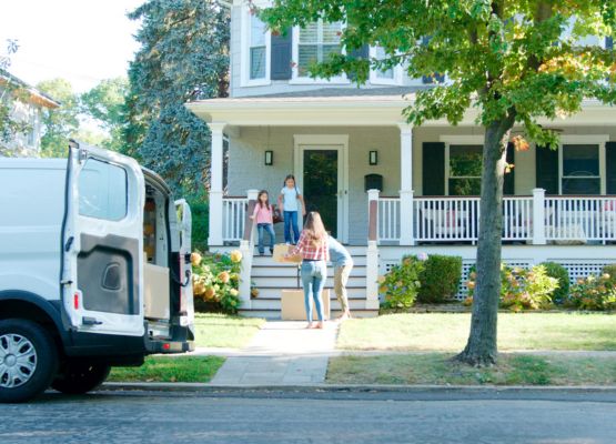 Moving truck in front of new home while people carry in boxes