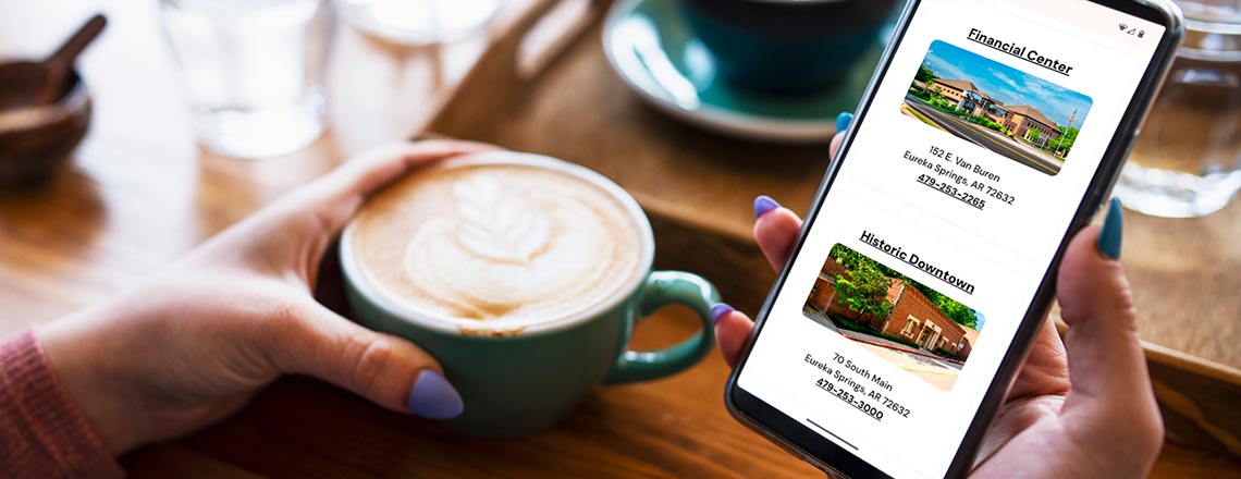 Person holding a phone and drinking coffee, looking at the location page for cs.bank